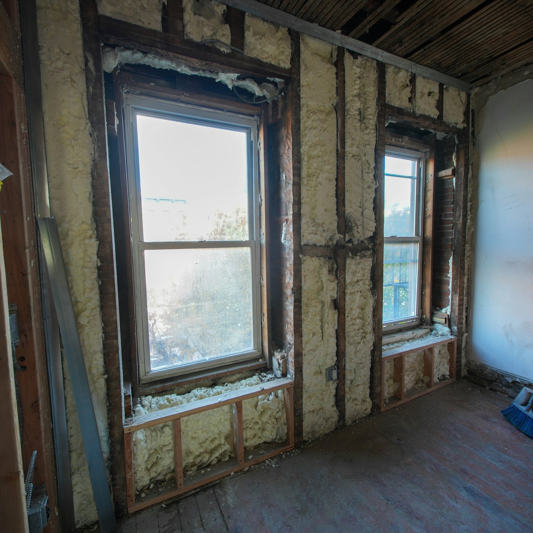 Room under renovation with closed-cell spray polyurethane foam filling the wall cavities around two windows