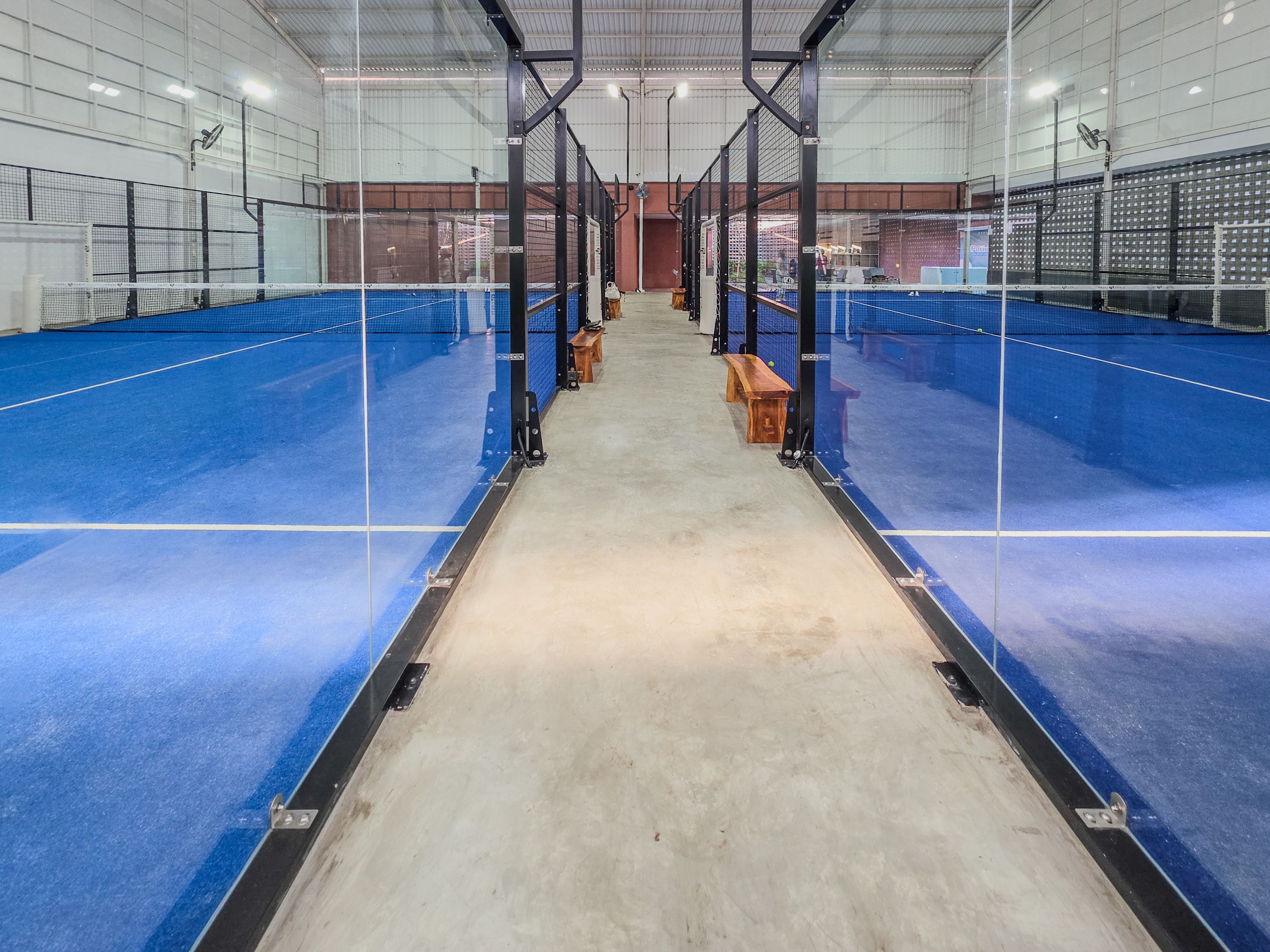 Indoor padel courts with bright blue synthetic flooring and glass walls
