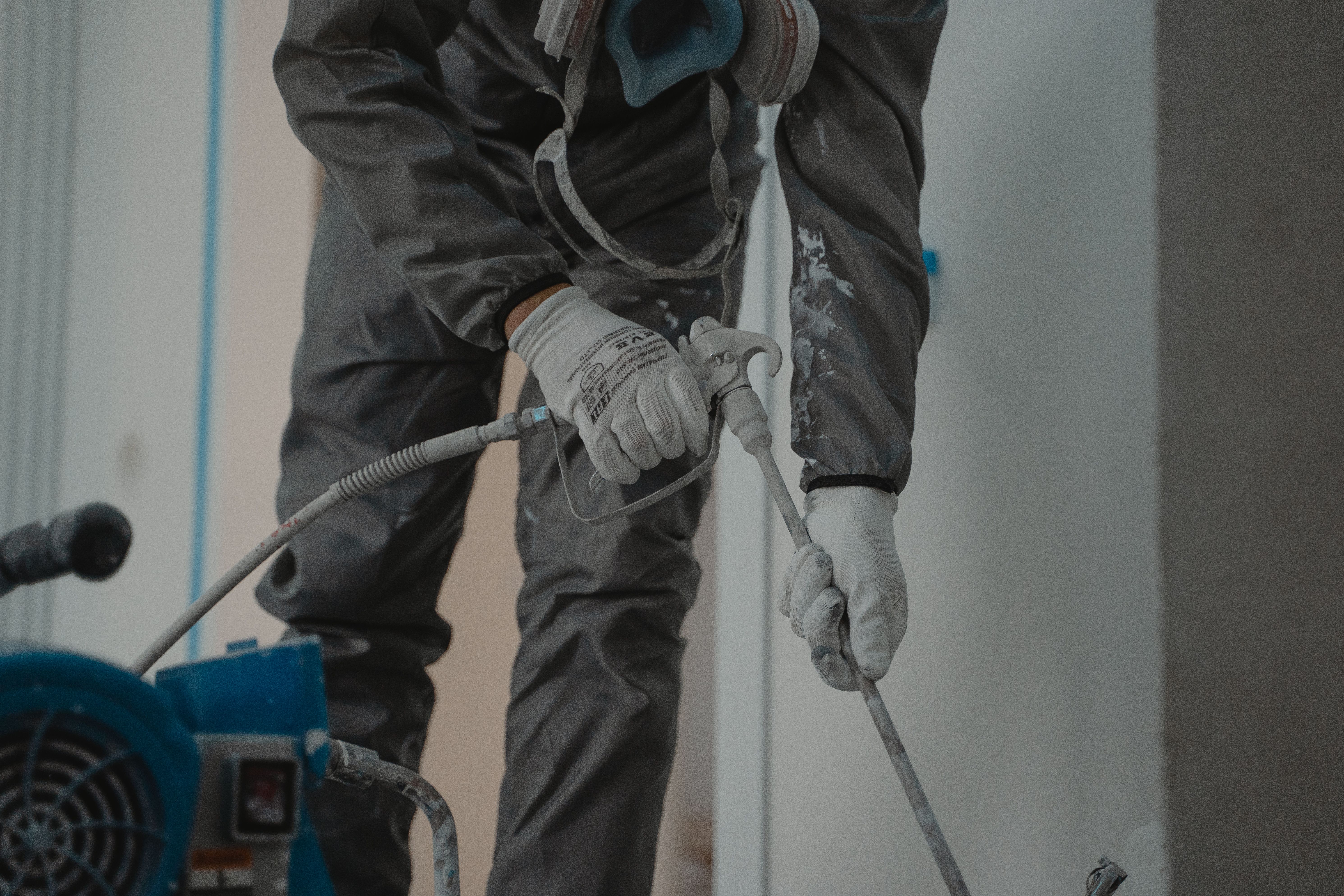 Operator in respirator working with a professional airless spray machine